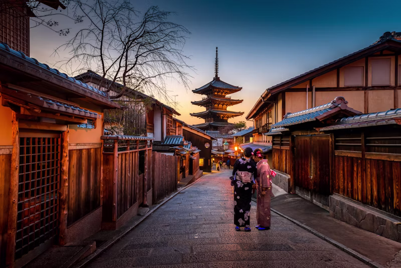Deux personnes en kimono dans une rue traditionnelle de Kyoto au coucher du soleil